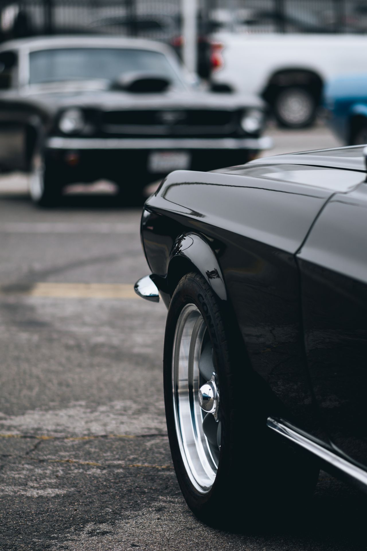 Detail van een klassieke zwarte auto met chroom velg op een parkeerterrein